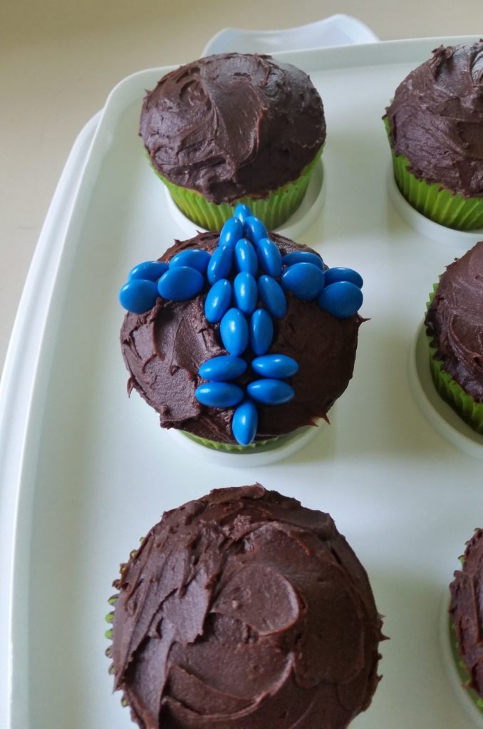 chocolate cupcakes on a platter. One is decorated with the shape of an airplane, made with candies