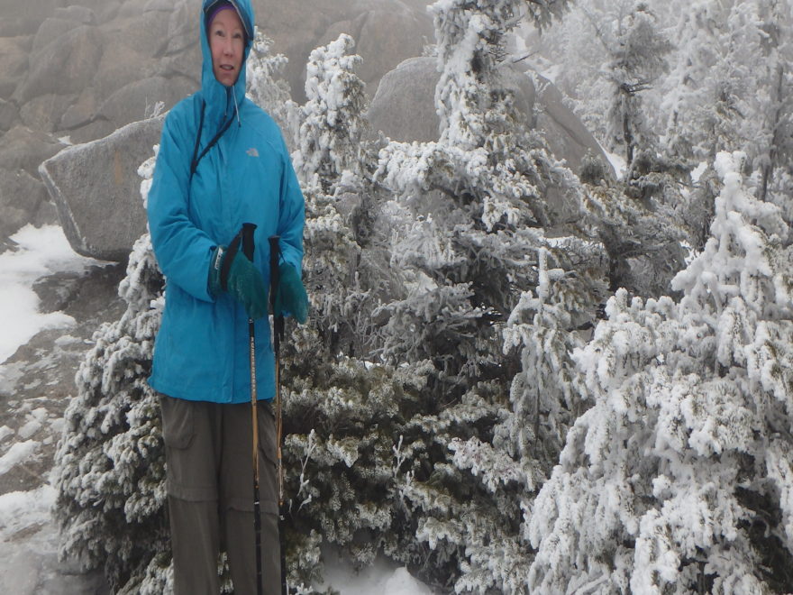 a woman snowshoeing up towards the bare rock summit of a mountain