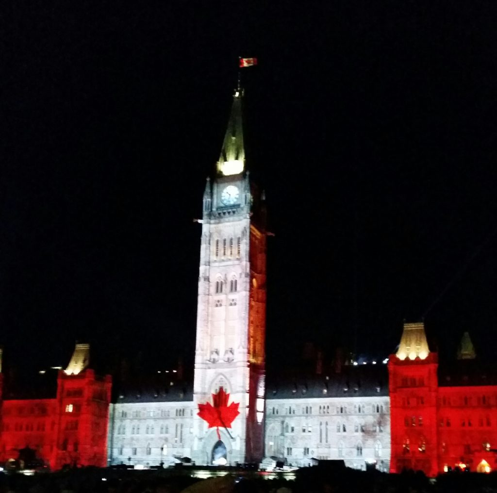 the Canadian Parliament building, with an image of the Canadian flag superimposed in lights