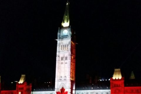 the Canadian Parliament building, with an image of the Canadian flag superimposed in lights