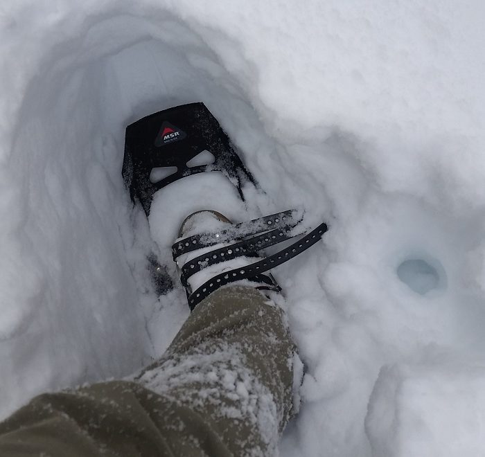 a woman snowshoeing up a steep mountain trail