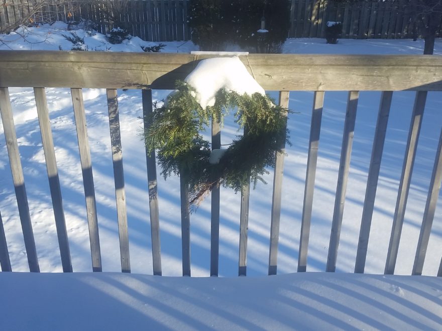 a Christmas wreath on the railing of a balcony, covered in snow