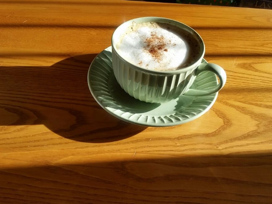 a cup of cappucino on a wooden table