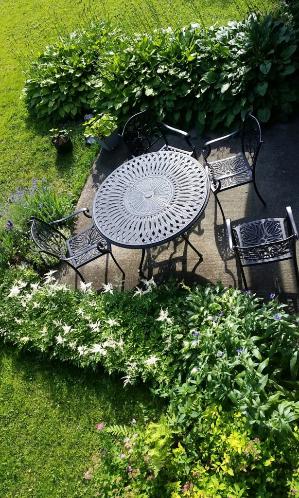 a wrought-iron table and chairs on a patio surrounded by gardens
