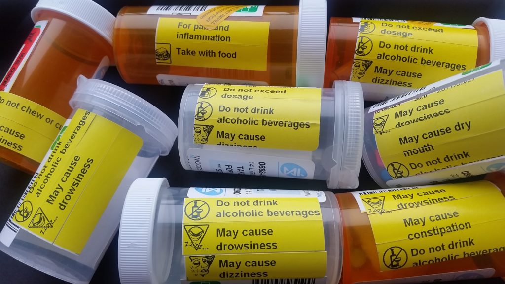 as assortment of 8 pill bottles, showing warnings for drowsiness, dizziness, constipation, dry mouth, etc.
