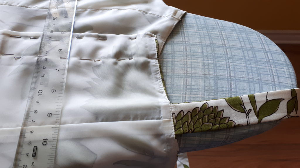 A woman's dress, inside out on an ironing board. The fabric has been pinned together, to take in the dress (make it smaller).