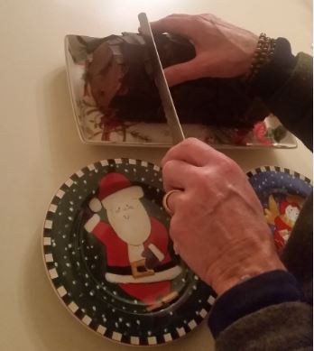 a man cutting a chocolate log-style cake, on a Santa Claus plate