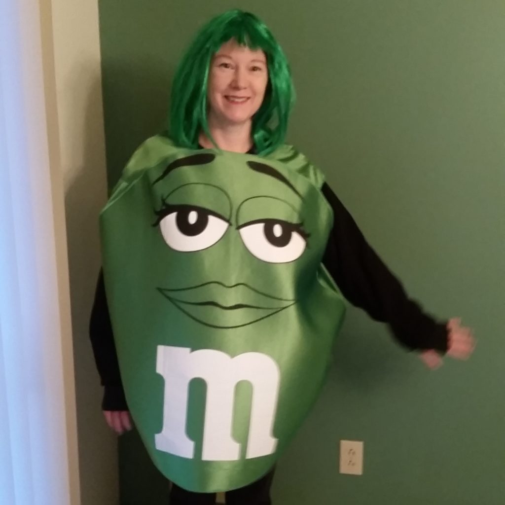 a woman dressed in costume, as a green M&M's candy and wearing a green wig