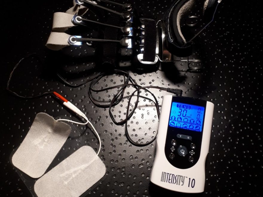 a poster stating "CRPS travel accessories", showing a TENS machine with 2 electrode patches and cables, along with a dynamic hand splint