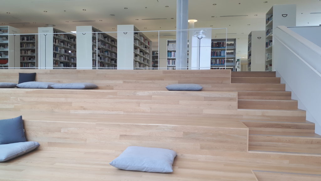 a seating area in a library, made to look like a large staircase, with large cushions for people to sit on or lean against