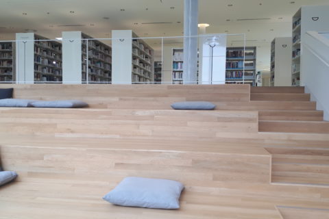 a seating area in a library, made to look like a large staircase, with large cushions for people to sit on or lean against