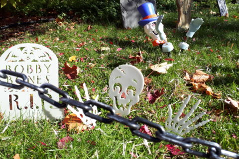 a front yard decorated with fake tombstones, to look like a cemetery for Halloween