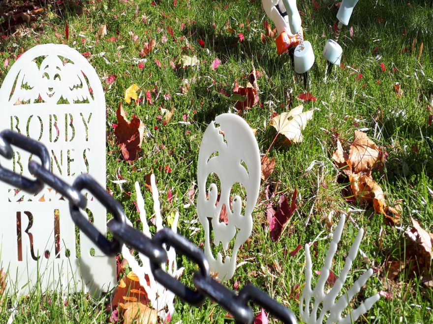 a front yard decorated with fake tombstones, to look like a cemetery for Halloween