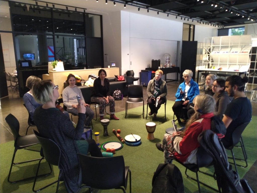 a group of 10 people, seated in a circle, participating in a group music therapy session during Play the Pain
