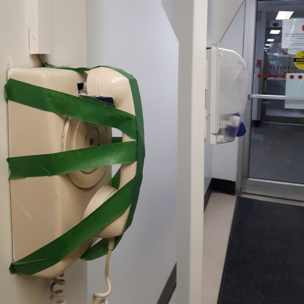 a wall-mounted phone at a hospital, with the receiver taped down so it can't be used