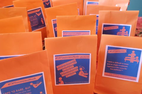 A grouping of paper bags on a table, each with a CRPS awareness message glued onto it