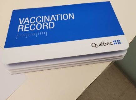 A vaccination record booklet on a table beside a of pneumonia vaccine