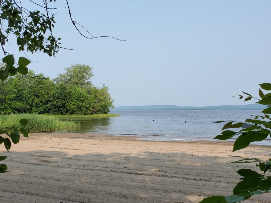 a beach overlooking a lake, on a sunny day