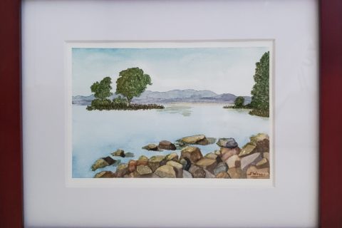 A watercolour painting of an island in the bay of a lake, seen from a rocky point