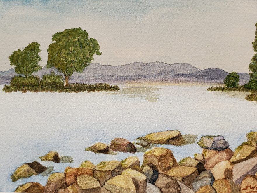 A watercolour painting of an island in the bay of a lake, seen from a rocky point