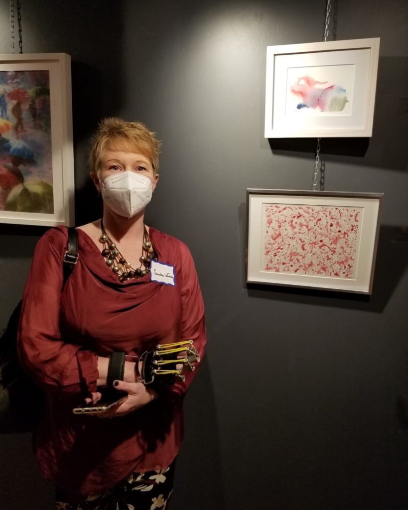 Sandra Woods beside two of her watercolour paintings, at the Centre d'art Montréal Art Centre (CAMAC) art gallery