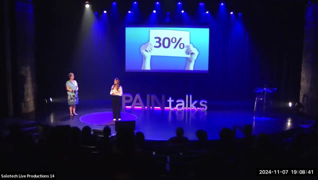 Zoha Deldar and Sandra Woods on stage, giving a presentation at PAINtalks 2024