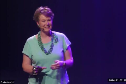 Sandra Woods on stage, giving a presentation at PAINtalks 2024