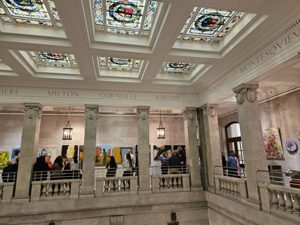 The stunning Conseil des arts de Montréal (Montreal Arts Council), originally Montréal's first public library from about 1917 and now a heritage building, with its ceiling of stained-glass panels across a 2-story atrium, and paintings displayed on the Mezzanine level. The entire interior is faced in Canadian white marble, with ornate carvings.
